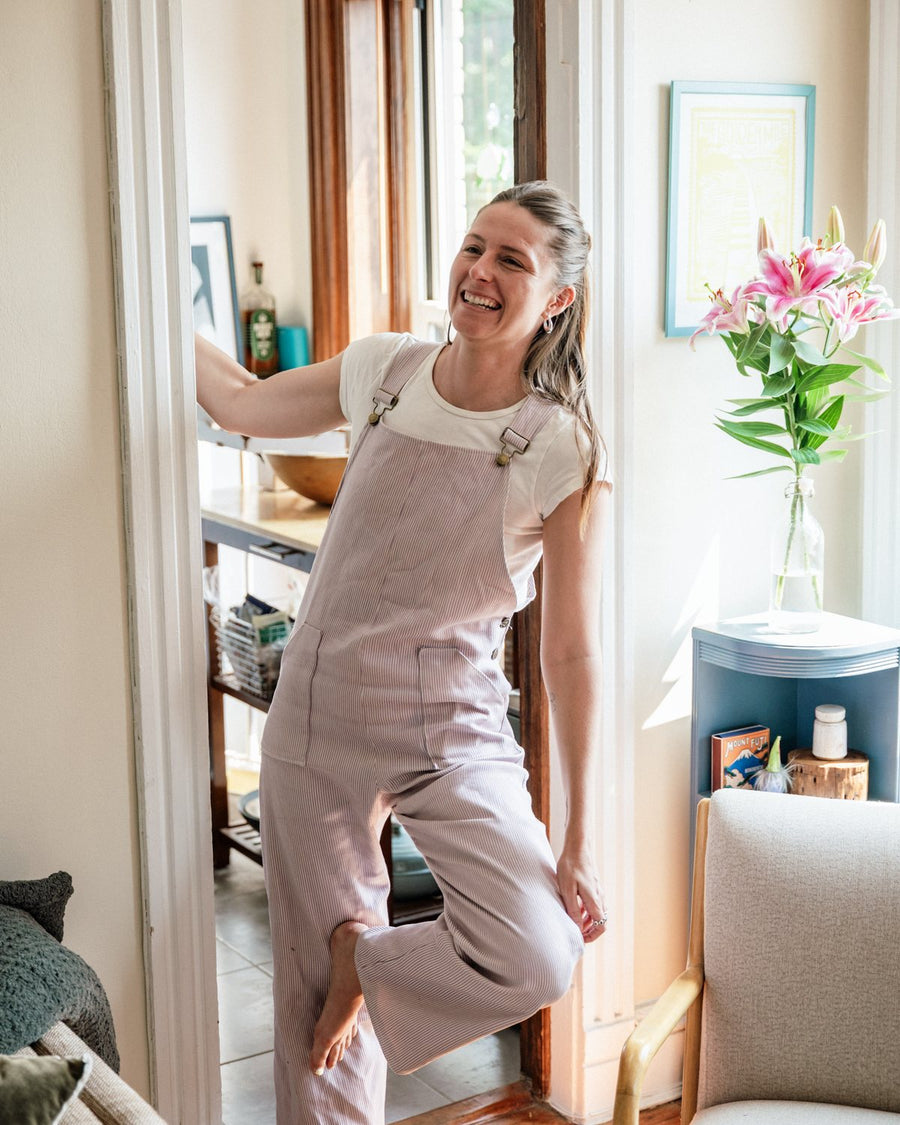 Blush overalls worn indoors, mid-movement